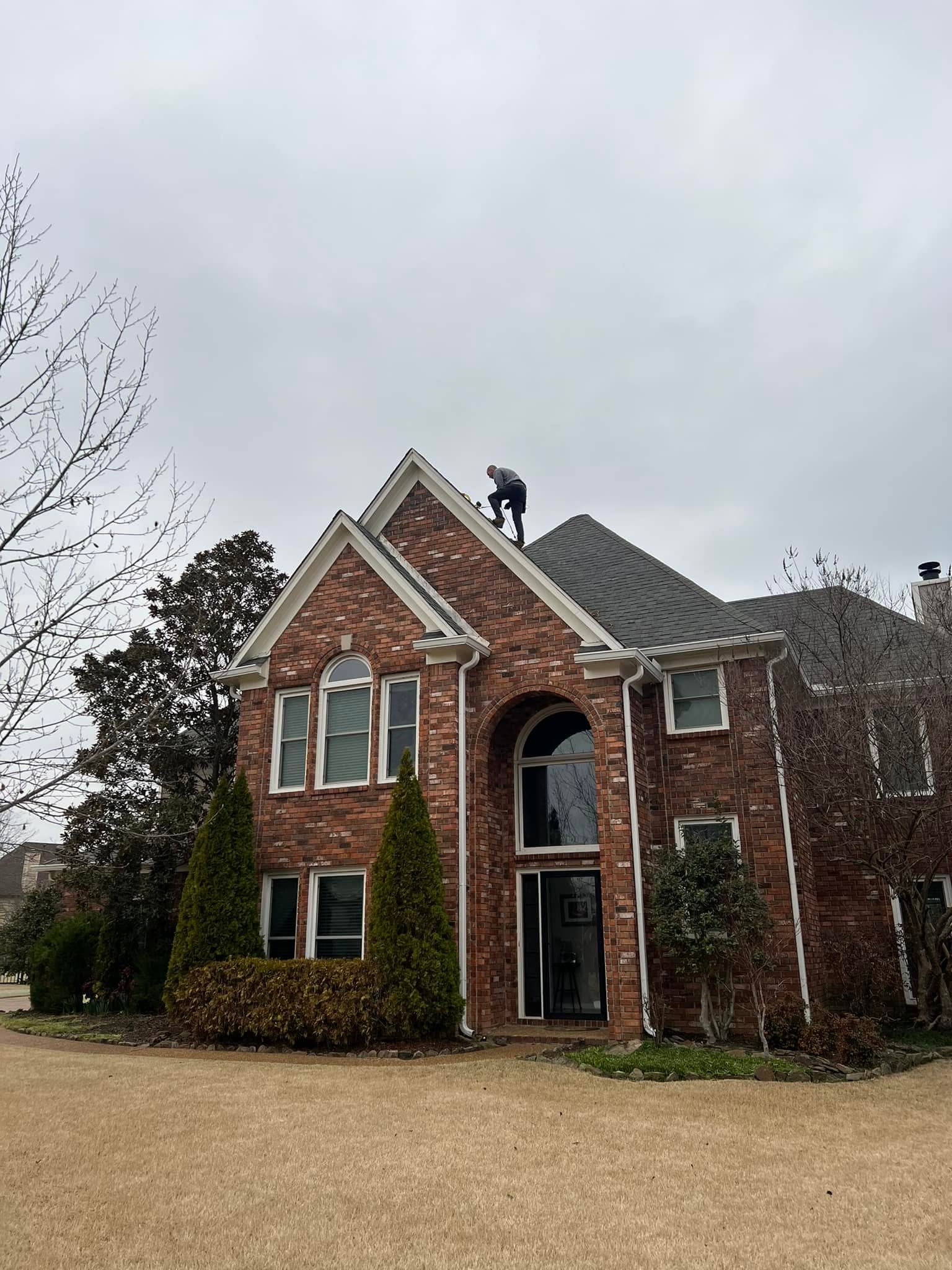 Roof inspection at the ridge of a two-story brick home