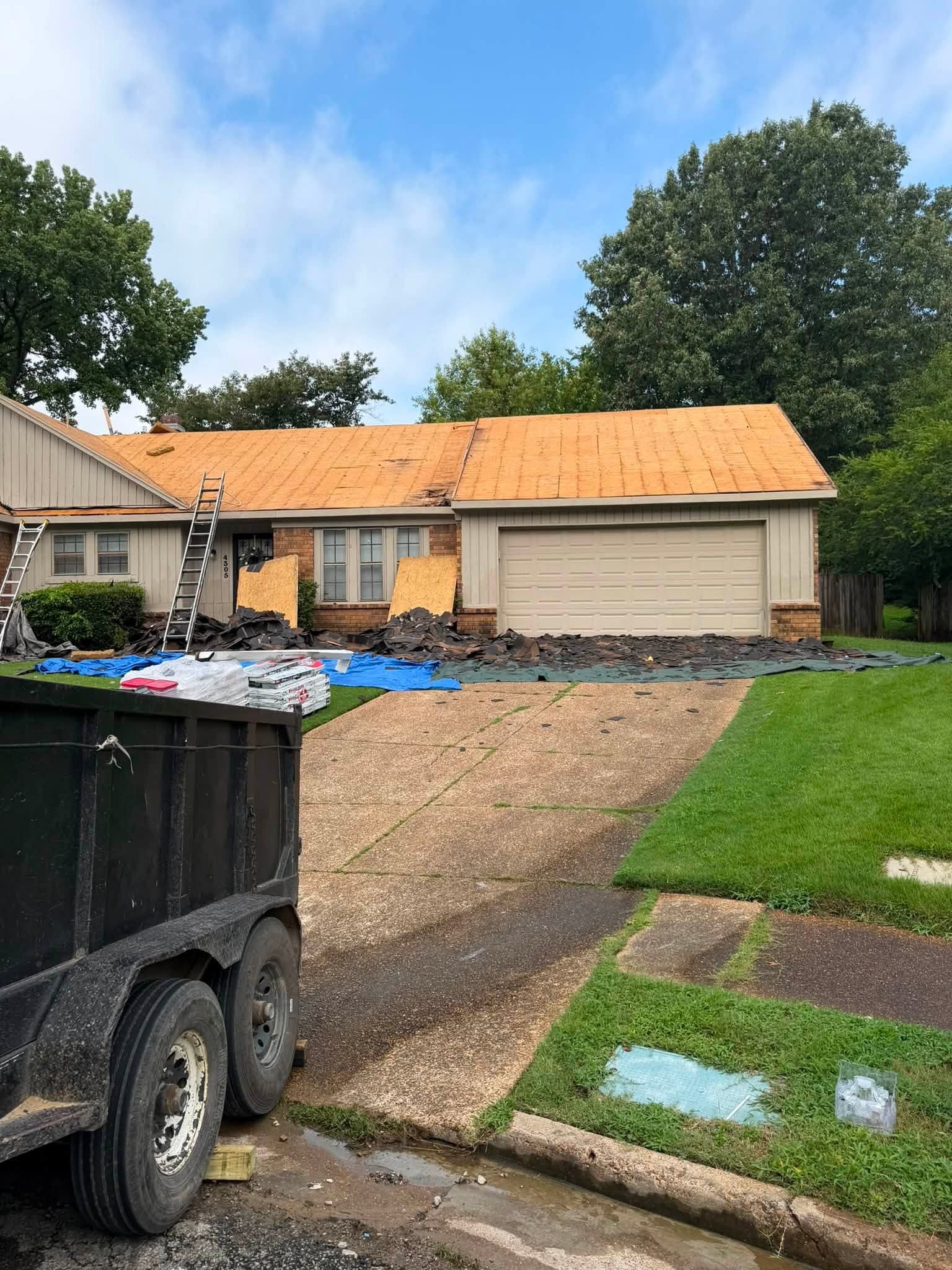 Full tear-off in progress with decking exposed and property protected by tarps